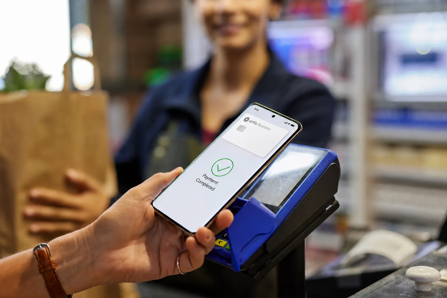 A shopper tapping their phone to pay with an Ortix Business card
